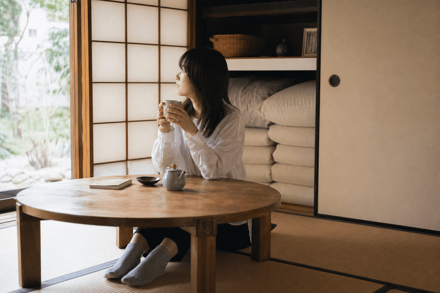 Person sitting on tatami floor at a low table in a Japanese room